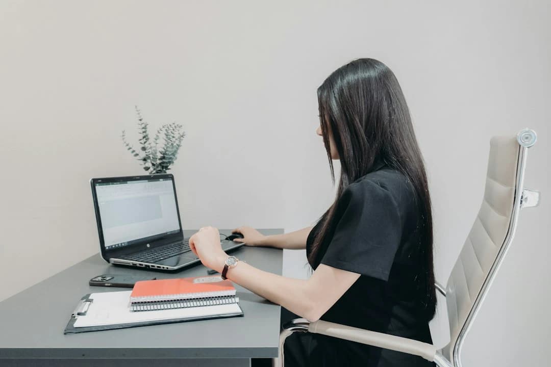 Woman working on a laptop at a desk with notebooks