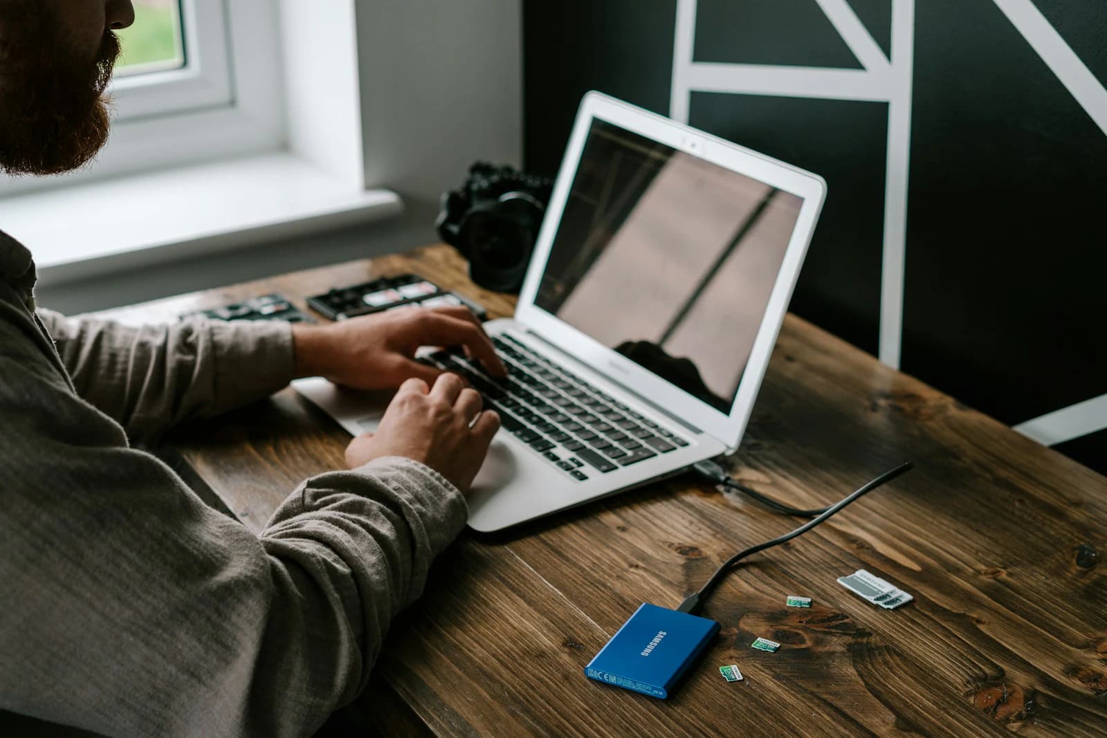 Person using a MacBook Air on a wooden table